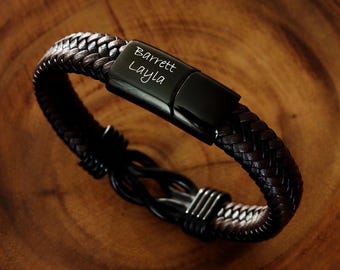 May include: A brown leather bracelet with a black metal clasp engraved with the names "Barrett Layla".