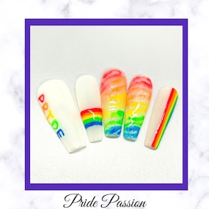 May include: Set of six white press-on nails with rainbow designs. One nail has the word "PRIDE" written on it. The nails are decorated with glitter and rainbow stripes.