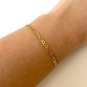 May include: A gold chain bracelet with a classic figaro link design.