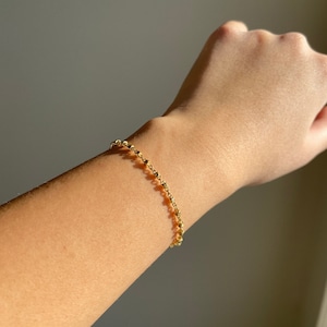 May include: A gold chain bracelet with small round beads.