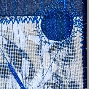 Macro view of hand embroidery and fine linen texture in indigo and white textile art, highlighting layered stitching details.