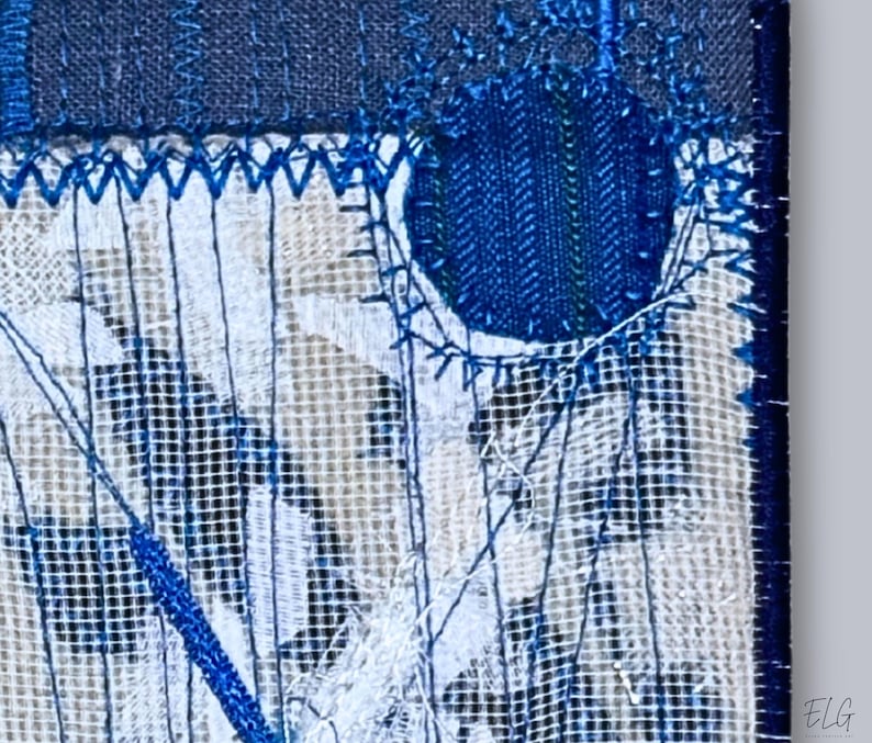 Macro view of hand embroidery and fine linen texture in indigo and white textile art, highlighting layered stitching details.