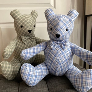 May include: Two plush teddy bears, one in a green plaid fabric and the other in a blue plaid fabric. Both bears have black eyes and a black nose, and are wearing a bow tie.
