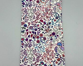 May include: A white fabric napkin with a floral pattern in shades of purple, pink, blue, and green. The flowers are small and densely packed, creating a busy and colorful design.