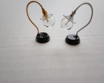 May include: Two miniature table lamps with a coiled wire base and a clear glass globe shade. One lamp has a gold base and the other has a silver base.
