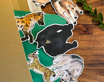 May include: Five animal stickers on a brown cardboard box. The stickers are of a hyena, a black bear, a deer, a lynx, and a wolf. The stickers are all in different poses and have a cartoonish style.