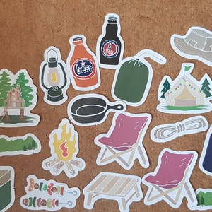 Könnte beinhalten: Ein Set mit 18 Camping-Stickern mit verschiedenen Motiven, darunter eine Kühlbox, eine Laterne, ein Lagerfeuer, ein Zelt, eine Tasse, eine Bratpfanne, ein Messer, ein Baum, eine Bierflasche, ein Schlafsack, ein Hut, eine Schüssel, ein Seil, ein Stuhl, ein Tisch und eine Fischdose. Die Sticker sind alle weiß mit bunten Illustrationen.