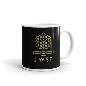 May include: A black ceramic mug with a gold graphic of the James Webb Space Telescope (JWST) logo. The logo features a honeycomb pattern and the text "JWST".