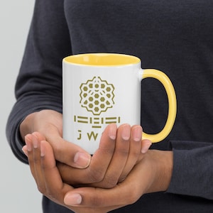 May include: A white ceramic mug with a yellow rim and handle. The mug features a gold honeycomb design and the text "J W" below it.