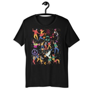 May include: Black t-shirt with a colorful graphic print of people dancing and celebrating. The design includes musical notes, stars, a peace sign, and a dove.