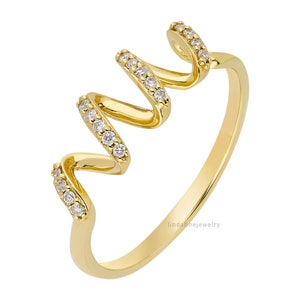 May include: A gold ring with a wavy design and small clear stones set in the band.