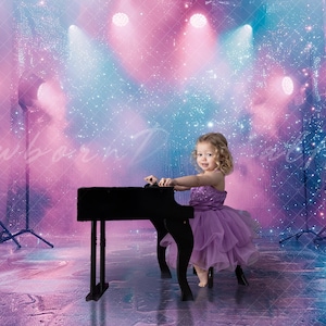 May include: A young girl in a purple dress sits at a black toy piano in front of a stage backdrop with pink and blue lights and glitter.