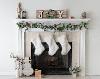 May include: A white fireplace mantel decorated for Christmas with a green garland, white fur stockings, and a wooden sign that reads "JOY".