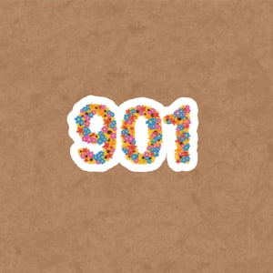 May include: A white sticker with the number "901" composed of colorful flowers in shades of blue, yellow, orange, and pink. The sticker is set against a brown background.