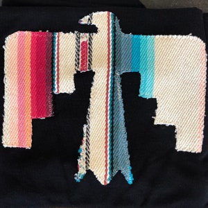 May include: A black t-shirt with a colorful embroidered bird design. The bird is made of fabric with stripes of pink, red, blue, and white.
