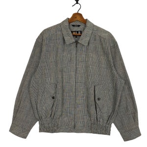 May include: A gray and black plaid zip-up jacket with a drawstring waist and two flap pockets. The jacket has a label that reads "D.A.S.C.O."