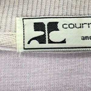 Puede incluir: Una etiqueta blanca con texto negro que dice "courr&egrave;ges and co". La etiqueta tiene un logotipo negro con las letras "C" y "C" entrelazadas.