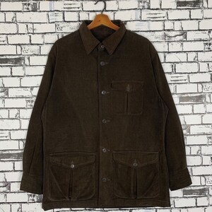 Puede incluir: Una camisa de pana marrón con cierre de botones, mangas largas y varios bolsillos.