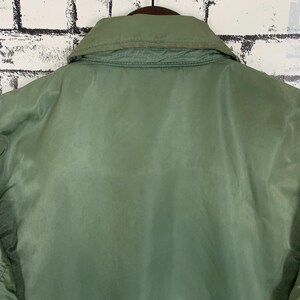 May include: A green jacket with a zipper closure and a collar. The jacket is made of a smooth, shiny fabric.