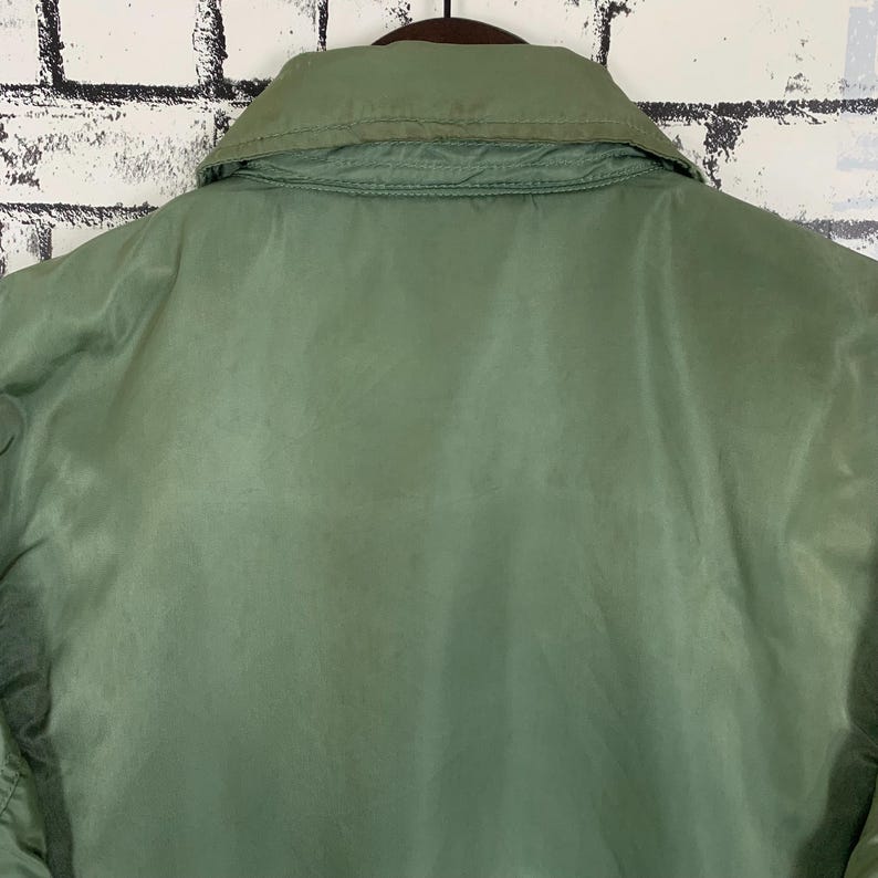 May include: A green jacket with a zipper closure and a collar. The jacket is made of a smooth, shiny fabric.