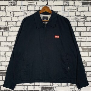 Puede incluir: Una chaqueta negra con cremallera con un logotipo rojo de Vans en el pecho izquierdo. La chaqueta tiene dos bolsillos en la parte inferior y una cremallera.