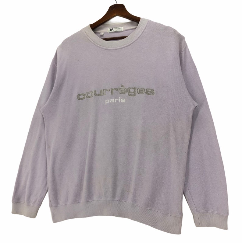 Puede incluir: Una sudadera de color lavanda con un logotipo bordado en gris que dice "Courr&egrave;ges Paris".
