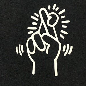 Puede incluir: Un dibujo de l&iacute;nea blanca de una mano con el dedo &iacute;ndice cruzado sobre el dedo medio. La mano est&aacute; rodeada de una estrella blanca.