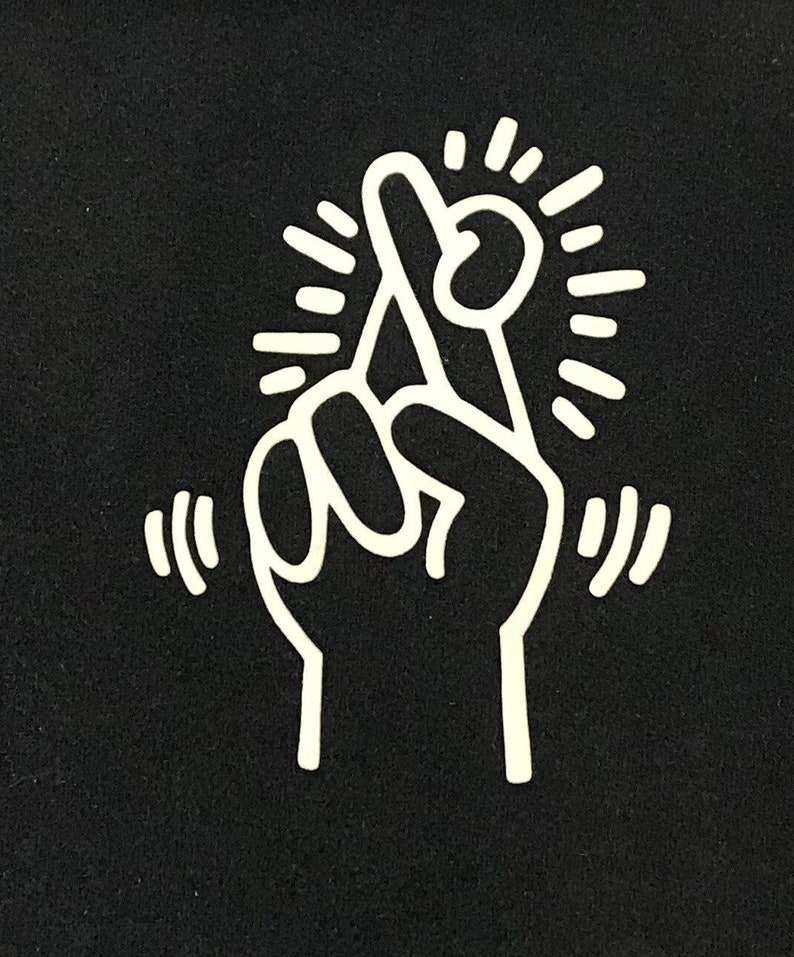 Puede incluir: Un dibujo de l&iacute;nea blanca de una mano con el dedo &iacute;ndice cruzado sobre el dedo medio. La mano est&aacute; rodeada de una estrella blanca.