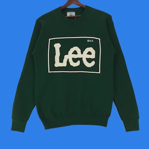 Op de afbeelding: Een donkergroen sweatshirt met een wit Lee-logo in een wit vierkant. Het logo is in een handschrift met een witte cirkel en de letters "MR" in de cirkel.