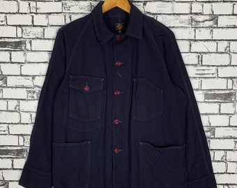 May include: A dark blue workwear jacket with red buttons and multiple pockets. The jacket has a button-up front and long sleeves.