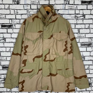 May include: A beige, brown and green camouflage jacket with a zip and button fastening. The jacket has two large pockets on the front and two smaller pockets on the chest.