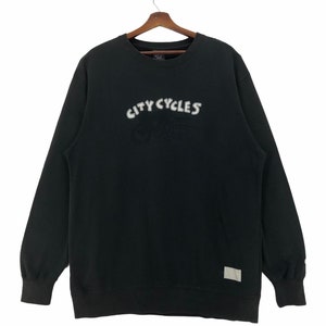 May include: Black sweatshirt with a white embroidered graphic of a motorcycle and the text "CITY CYCLES".