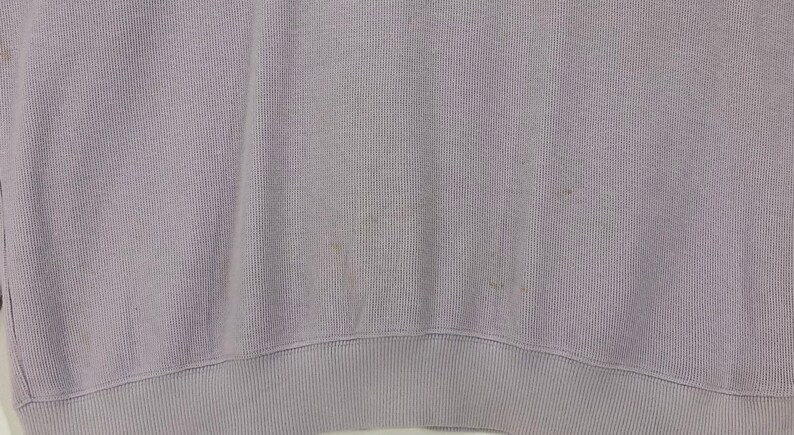 Puede incluir: Una sudadera de color lila claro con textura acanalada. La sudadera tiene cuello redondo y mangas largas.