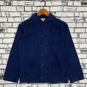 Puede incluir: Una chaqueta de trabajo azul marino con cierre de botones, cuello y dos bolsillos grandes. La chaqueta tiene una etiqueta blanca con el texto "Le Glazik" en la parte inferior derecha.