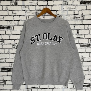 Puede incluir: Sudadera gris con letras negras que dicen "St. Olaf Grandparent".