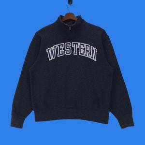 Puede incluir: Una sudadera gris oscura con cierre de cremallera a la mitad y la palabra "WESTERN" en letras blancas y azules en la parte delantera.