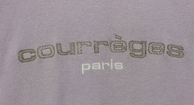 Puede incluir: Una sudadera de color lavanda con el texto "Courr&egrave;ges Paris" bordado en gris y blanco.