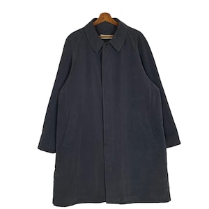 May include: A dark grey long-sleeved coat with a button-up front and a collar. The coat has two pockets on the front and a single button at the waist.