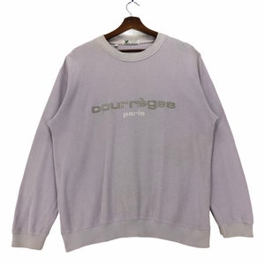 Puede incluir: Una sudadera de color lavanda con el texto "courr&egrave;ges paris" bordado en la parte delantera en color plateado.