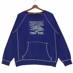 May include: A blue sweatshirt with a white stitched outline. The sweatshirt has a large graphic of a wolf with the text "Nevada Wolf Pack" printed on it.