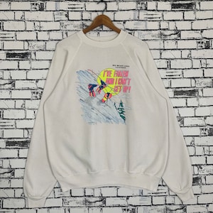 Puede incluir: Sudadera blanca con un gráfico de un esquiador cayendo por una montaña. El gráfico dice "Big Bear Lake, California. ¡Me he caído y no puedo levantarme!"