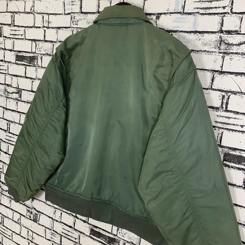 May include: A green bomber jacket with a zipper closure and a ribbed collar.