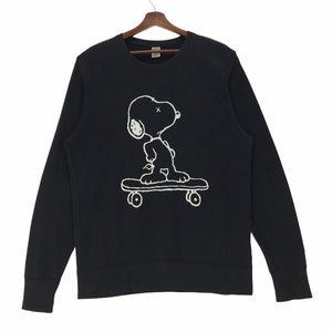 May include: Black long-sleeve sweatshirt with a white outline of Snoopy skateboarding. The text "Uniqlo" is visible on the tag.