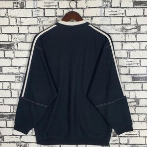 Puede incluir: Una sudadera de manga larga azul oscuro con ribetes blancos alrededor del cuello y las mangas. La sudadera tiene una textura acanalada.