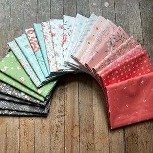 May include: A collection of 18 fabric squares in various shades of green, pink, and white with floral patterns. The fabric squares are arranged in a semi-circle.