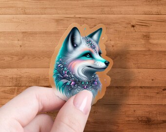 May include: A sticker featuring a detailed illustration of a fox with a turquoise, pink, and purple jeweled collar. The fox has a white face with blue eyes and a pink nose.