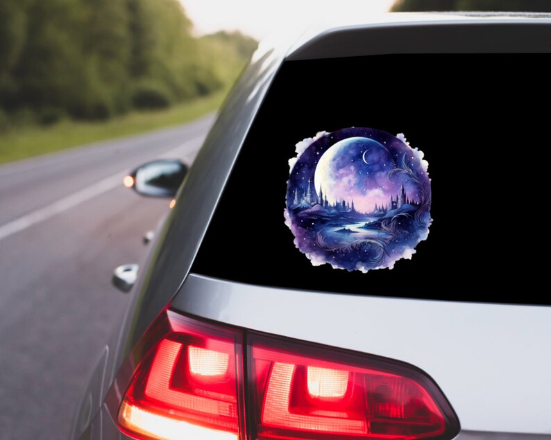 May include: A round car decal featuring a watercolor painting of a nighttime fantasy scene. The design includes a large, bright moon, a river, and silhouetted castles and trees, with a color palette of blues, purples, and white.