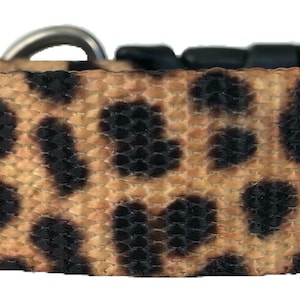 Puede incluir: Un collar de perro de color marrón y negro con estampado de leopardo y hebilla plateada.