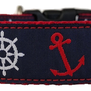 Può includere: Un collare per cani blu navy con ricami a tema nautico rosso e bianco. Il collare presenta ancore e ruote di nave.