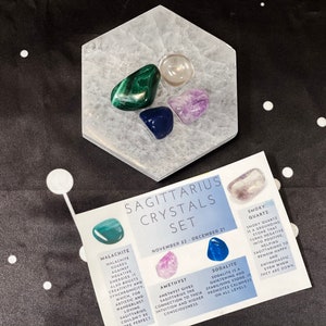 May include: A set of crystals for the Sagittarius zodiac sign. The set includes smoky quartz, amethyst, sodalite, and malachite crystals. The crystals are arranged on a white hexagonal crystal plate. The crystals are labeled with their names and their astrological meanings.